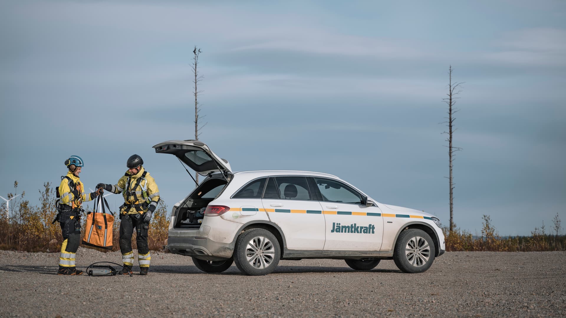 Två personer i arbetskläder lastar ur en bil